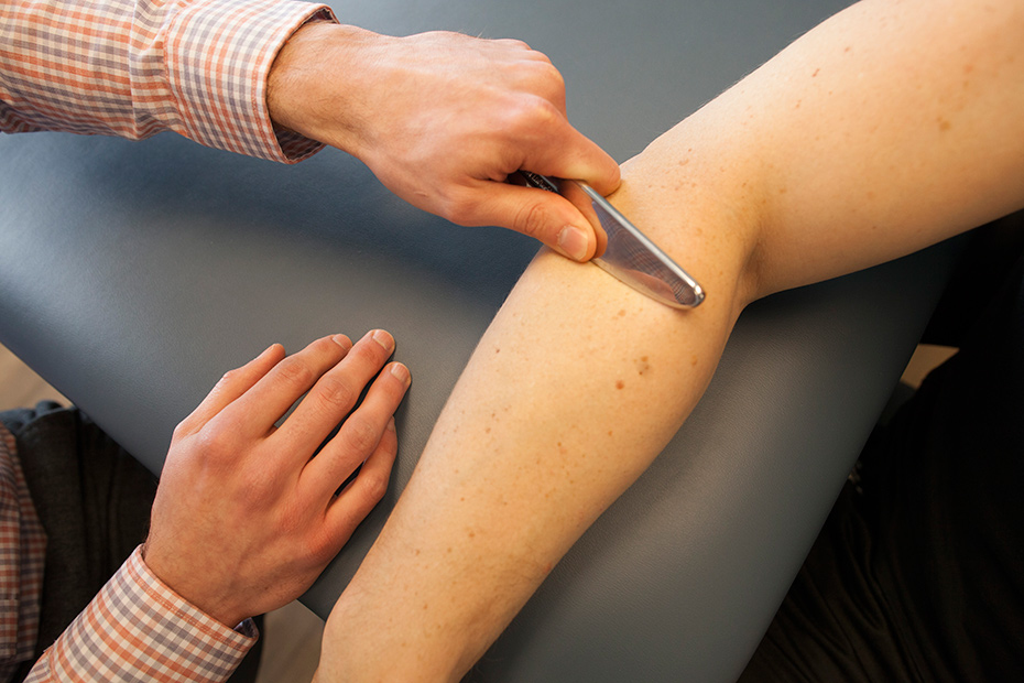 Therapist using an IASTM tool on a patient's forearm